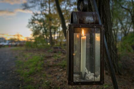 An old-fashioned candle lit lantern during early evening hoursの写真素材