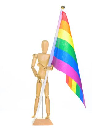 Small wooden mannequin holding a rainbow flag, isolated on a white backgroundの写真素材