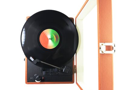 Top view of an old-fashioned suitcase record player and turntable with a spinning vinyl record,...