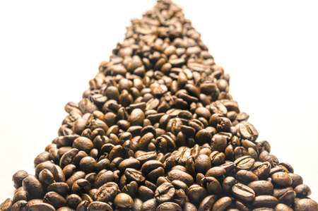 Roasted coffee beans forming a path, leading into the distance, isolated on a white background