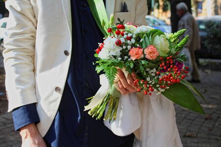 A man dressed in a white suit with a wedding bouquet in handsの写真素材