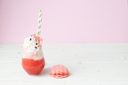 Watermelon cocktail with whipped cream in a glass. On the white table.の写真素材