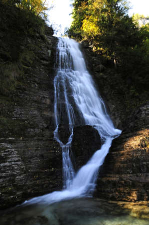 Alpine waterfall in the forest during a sunny day