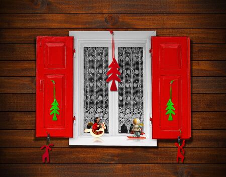 Window with red shutters and Christmas decorations on wooden wallの写真素材