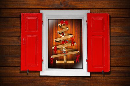 Christmas tree seen through a wooden window with red shuttersの写真素材