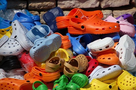 Group of colorful plastic clogs displayed for sale at marketの写真素材