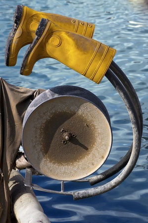 Yellow rubber boots hanging on to fishing winch - concept of fisherman's restの写真素材
