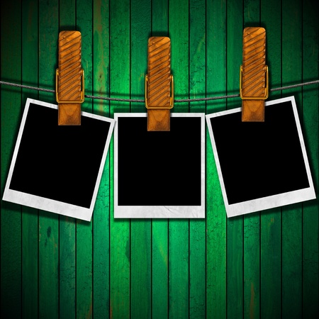 Three blank photos hanging on a steel cable on green old wall の写真素材