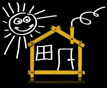 Yellow meter tool forming a house with sun, door and window on black backgroundの写真素材