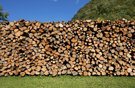 Dry chopped firewood logs in a pile on blue skyの写真素材