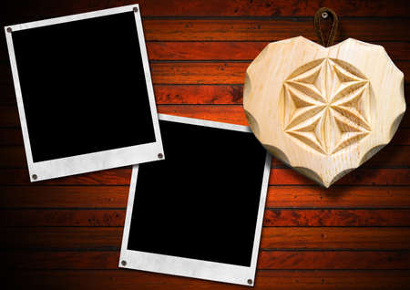 Two instant photo frames on brown wooden wall with handmade wooden heart の写真素材