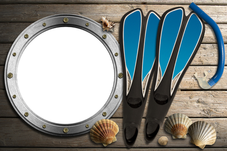 Metal empty porthole with seashells, blue flippers and blue snorkel diving on wooden floor with sandの写真素材