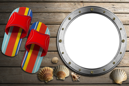Metal empty porthole with seashells and colored sandals on wooden floor with sandの写真素材