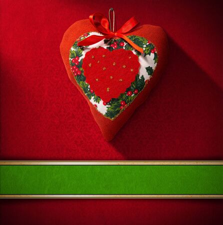 Christmas heart hanging on red velvet background with ornate floral seamless and green plaqueの写真素材