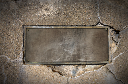 Old metal plate with bolts on cracked concrete wallの写真素材