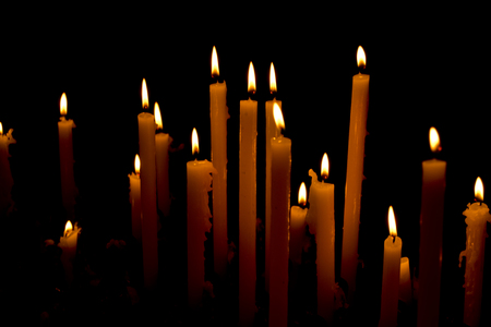 A group of warm glowing candles on dark backgroundの写真素材