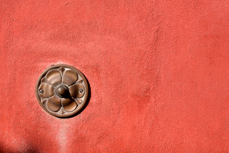 Old brass doorbell button on red wall in Tellaro, ancient small village of Liguria in Italy