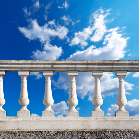 Old white stone balustrade with blue sky and clouds in the backgroundの写真素材