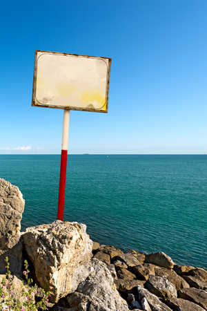 Blank signboard with red and white metal pole in a cliffの写真素材