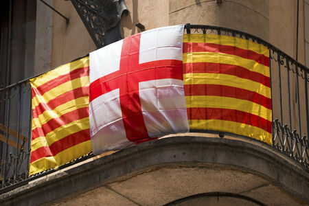 Flag of Catalonia striped red and yellow and Barcelona flag with the cross of Saint George in Barcelona, Catalonia, Spainの写真素材