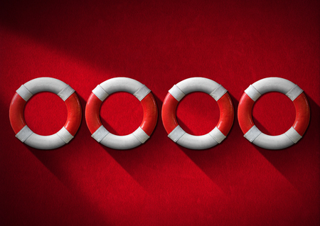 Four red and white lifebuoys hanging to a red velvet wall - Concept of helpの写真素材