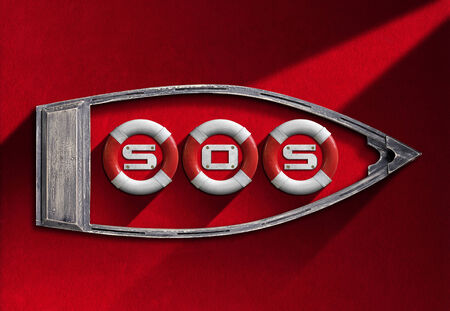 Three red and white lifebuoys hanging in a small wooden boat with the text SOS in a red velvet wall  - Concept of helpの写真素材