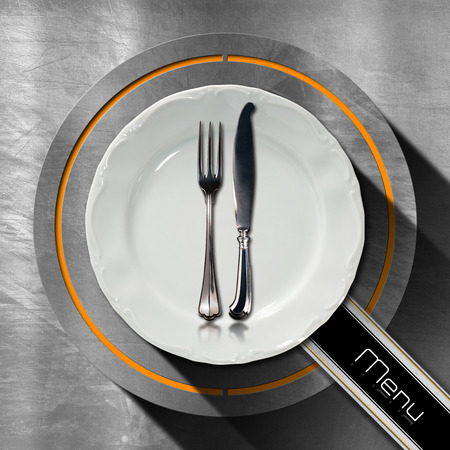 Steel stainless background with circle, empty plate and cutlery, diagonal black band with text, menu. Template for a restaurant food menuの写真素材