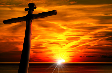 Cross silhouette at the beautiful sunset over the sea with cloudy sky.の写真素材