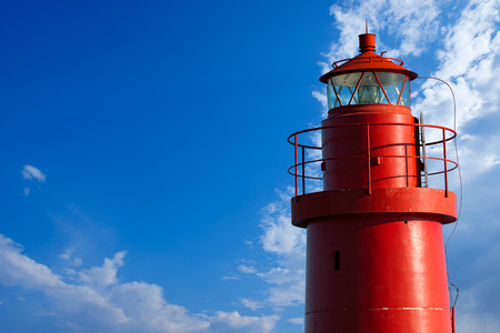 The top of red lighthouse in the La Spezia harbor, Liguria, Italy. On blue sky with cloudsの写真素材