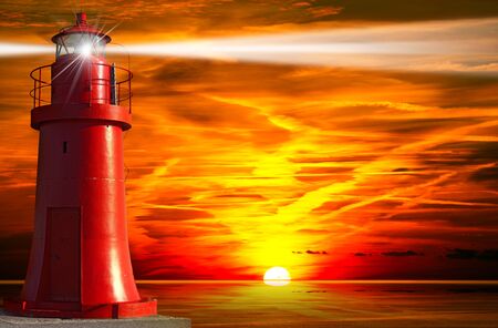 Red and metallic lighthouse with light beam at sunset with cloudsの写真素材