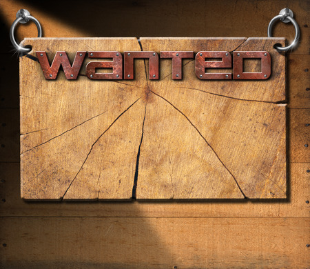 Wooden cracked sign with metallic text Wanted in the style of the wild west. Hanging on a wooden wall.の写真素材