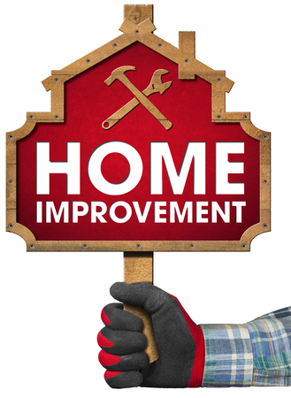 Hand with work glove holding a wooden sign in the shape of house with text Home Improvement. Isolated on white backgroundの写真素材