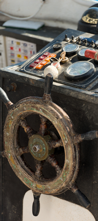 Detail of an old blurred console with wooden helm wheel of a fishing boat. Liguria, Italy