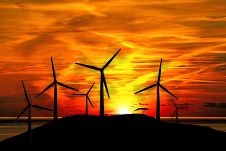 Six silhouettes of wind turbines in mountain with a beautiful sunset over the sea