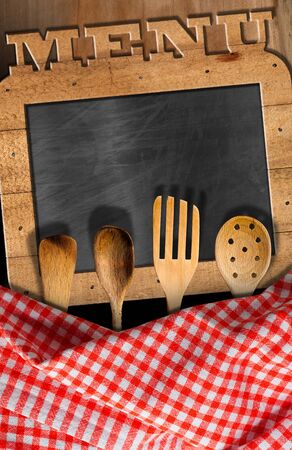 Empty blackboard with wooden frame and text Menu, with wooden kitchen utensils. On a table with checkered tableclothの写真素材