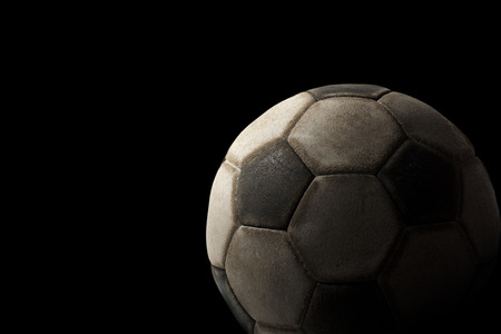 Detail of a old black and white soccer ball on a black background with dark shadowsの写真素材