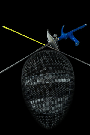 Fencing foil equipment. Two fencing foils with pistol grip and tip, and a fencing mask. Isolated on black backgroundの写真素材