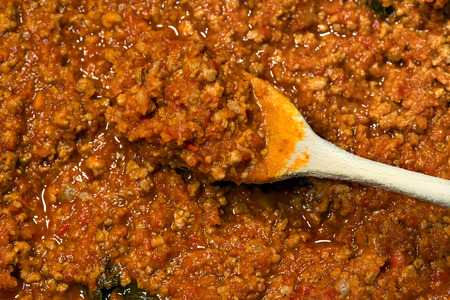 Detail of italian meat sauce (Bolognese sauce or ragu) cooked with meat, vegetables and tomato sauce, with a wooden spoonの写真素材