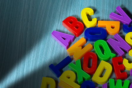 Close up of a colorful magnetic letters on a wooden desk. Illuminated ABC textの写真素材