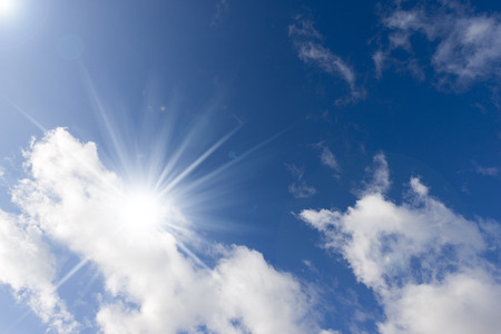 Detail of a horizontal blue sky with sun rays and clouds