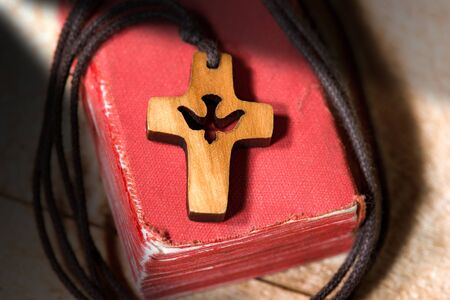 Small wooden crucifix with a dove and rope on an old Holy Bibleの写真素材