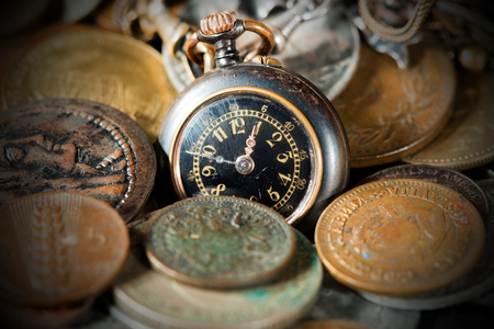 Time is money - Small pocket watch and old and vintage metallic coinsの写真素材