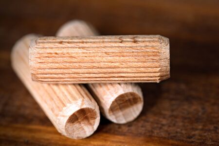 Macro photography of three wooden dowels on a dark wooden work table