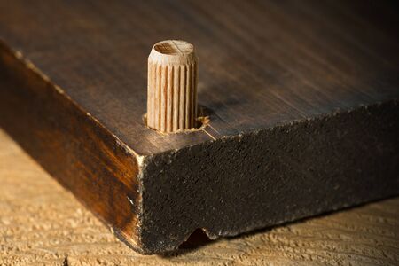 Macro photography of a wooden dowel in the hole of a wooden board