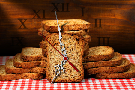 Rusks of wholemeal flour on a table with a clock made with a rusk. Concept of time for a healthy...