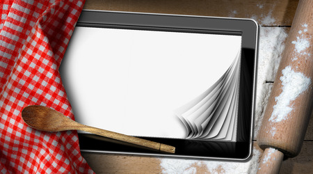 Baking background with a tablet computer with blank pages. On a wooden table with flour, rolling pin, spoon and a checkered tableclothの写真素材