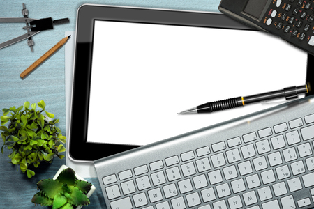 Office desk with a blank digital tablet computer, keyboard, pencil, calculator, drawing compassの写真素材