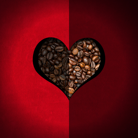 Red velvet background with a heart-shaped hole with roasted coffee beans insideの写真素材