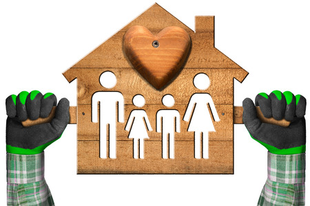 Hands with work gloves holding a wooden model house with a symbol of family and heart. Isolated on a white backgroundの写真素材