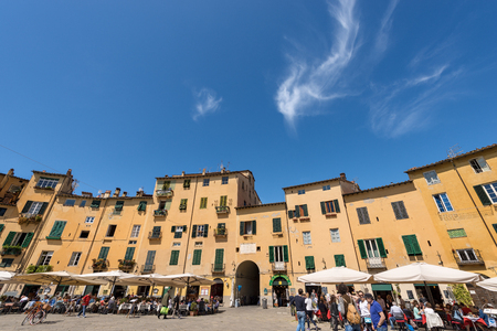 LUCCA, ITALY - APRIL 16, 2017: Tourists and locals visit the ancient Town square (Piazza dell'Anfiteatro - Amphitheater Square) in the small old Town of Lucca, Toscana (Tuscany), Italy, Europeのeditorial素材